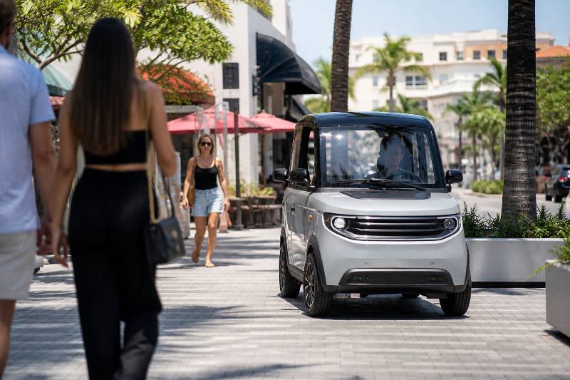 Diverse group using Madjax Urban Mobility vehicles in a South Florida community